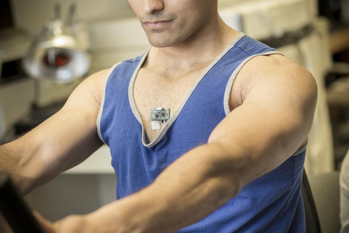co-author Amay Bandodkar wears the ChemPhys patch while using an exercise bike in a lab at the Center for Wearable Sensors. (Image Credit: Jacobs School of Engineering/UC San Diego)