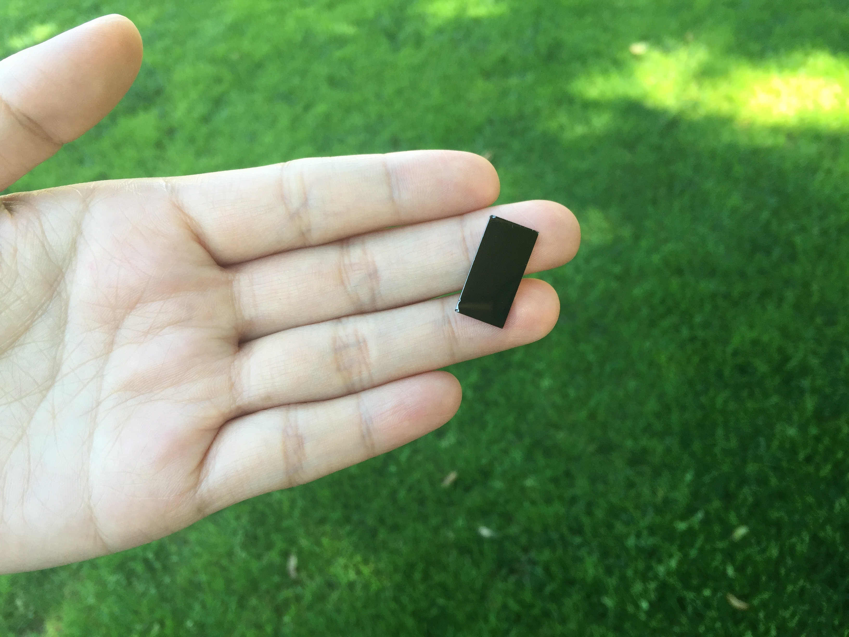 A researcher holds a small, nanostructured device that uses sunlight to disinfect water. By harnessing a broad spectrum of sunlight, it works faster than devices that use only ultraviolet rays. (Jin Xie/Stanford University)
