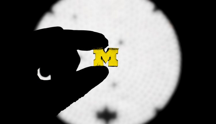 A new way to 3D print, developed at the University of Michigan, uses two lights to control the solidification of resin, enabling complex shapes to be pulled from a vat at 100 times the print speed of conventional 3D printers, and was demonstrated by printing a block M in a U-M chemical engineering lab in Ann Arbor, MI on December 6, 2018. This project was co-led by Timothy Scott, associate professor of chemical engineering and Mark Burns, T.C. Chang Professor of Engineering and professor of chemical engineering and biomedical engineering.(Image Credit: Evan Dougherty/Michigan Engineering)