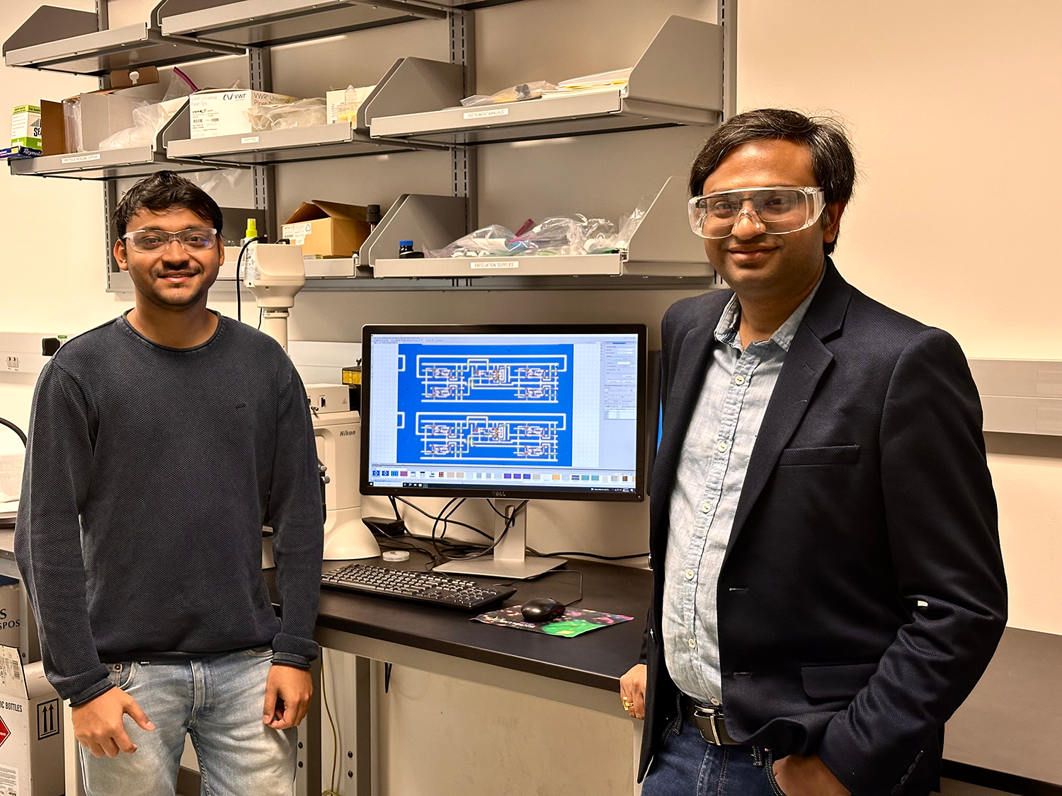 Two people stand in a lab with a computer display between them